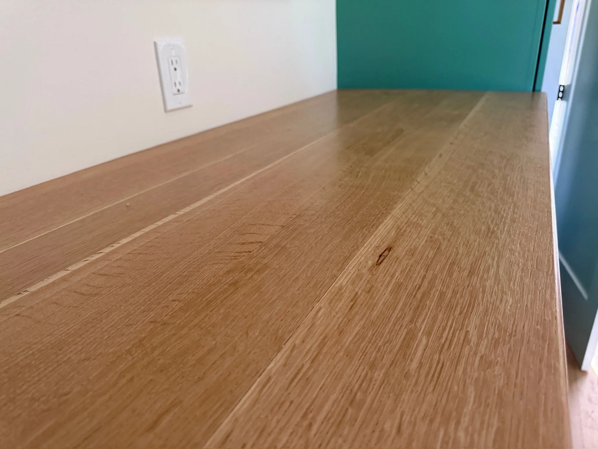 Close view of the figured oak top meeting the green cabinetry